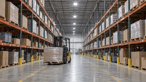 Wide distribution center aisle lined with loaded selective pallet racking, with several feet of empty vertical space above the top load level